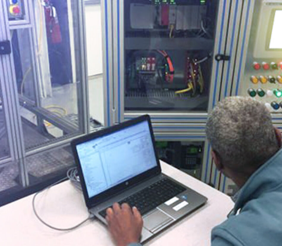 Man sitting in front of robotic training cell learning automation systems