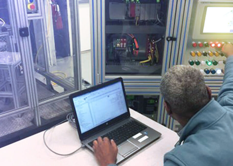 Man sitting in front of robotic training cell learning automation systems