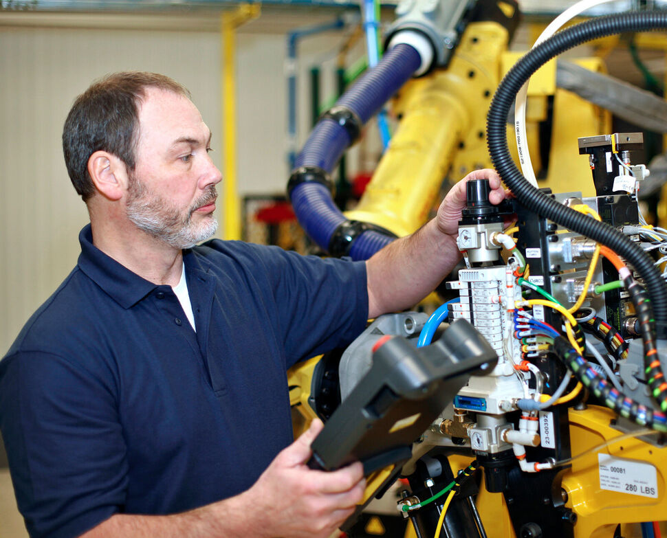 Man next to a robot programming with teach pendant