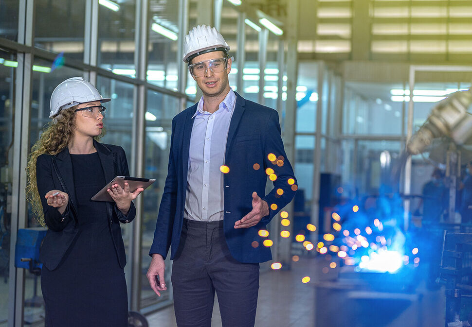 Man and woman standing next to industrial robots for automation systems training